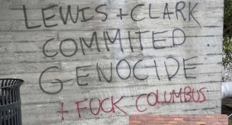 Graffiti on a wall that reads: Lewis + Clark commited genocide + fuck Columbus